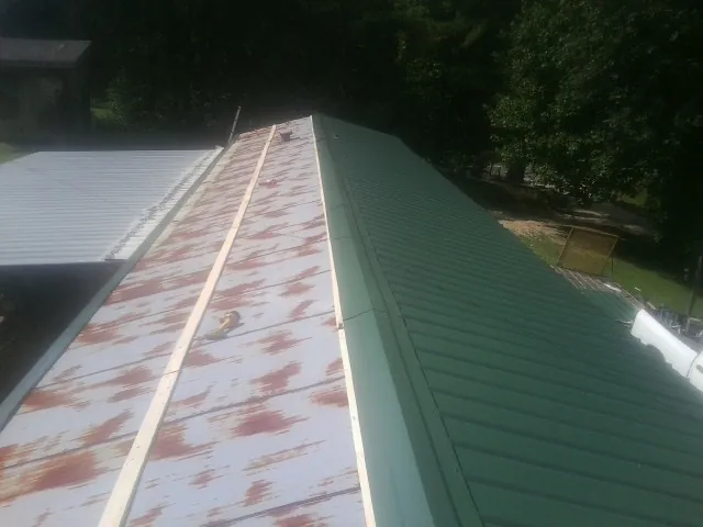 Old rusted panels beside newly installed green metal roofing — Wind Damage Roof Repair by Roofing Brothers in Cross Plains
