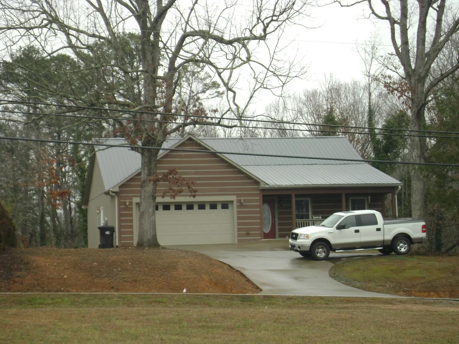 Gray metal roof on a log sided house with an attached two car garage in Cross Plains